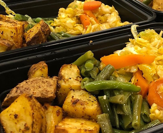 Meal prep trays with roasted potatoes, green beans, and mixed sautéed vegetables.