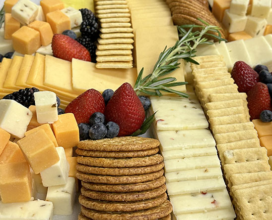 Cheese and cracker platter with assorted cubed cheeses, sliced cheeses, crackers, berries, and rosemary