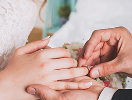 Close-up of a groom placing a wedding ring on the bride’s finger during the ceremony.